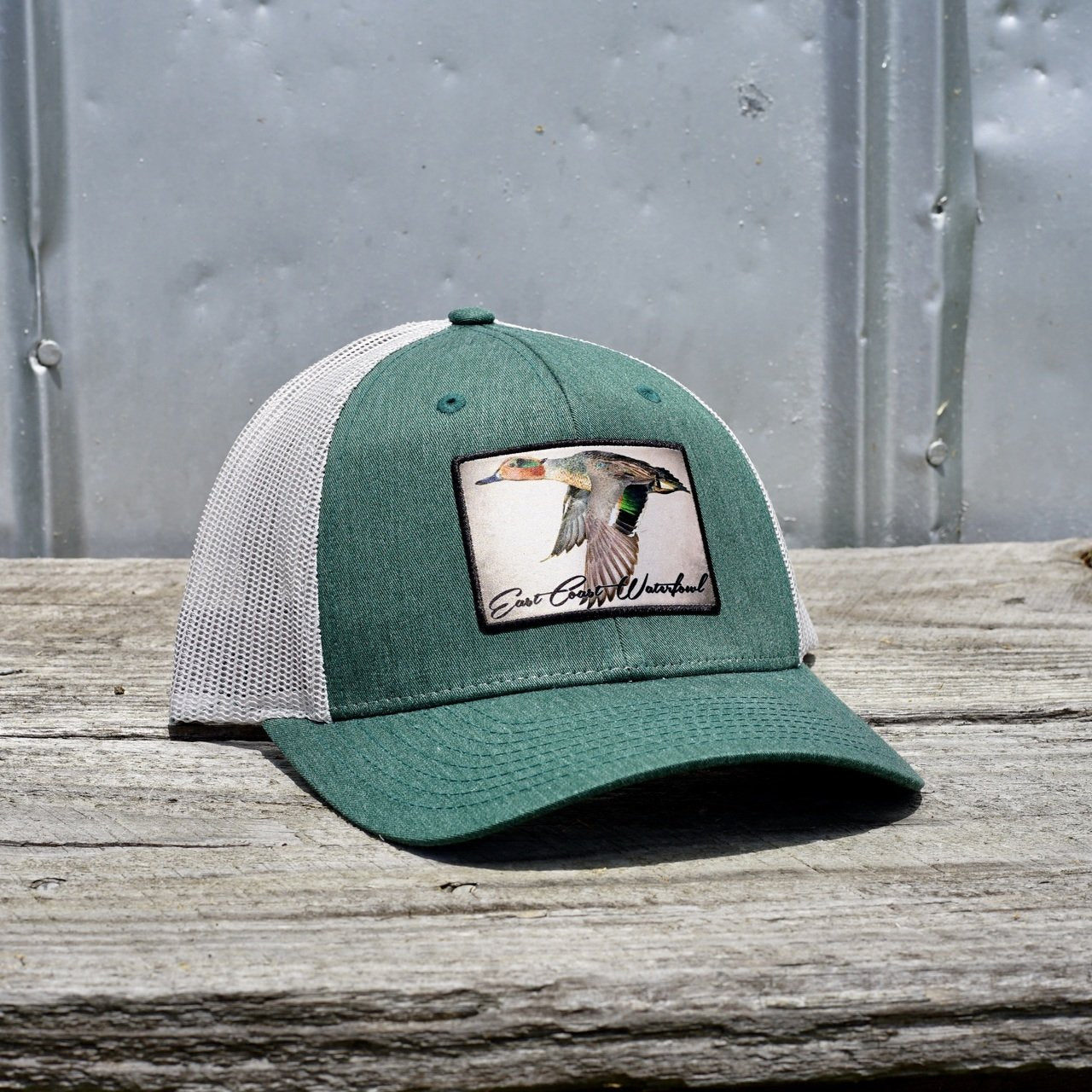 http://hometownheritageclothing.com/cdn/shop/products/White-Teal-Duck-Patch-Trucker-Hat-by-East-Coast-Waterfowl_9e22638c-c3c4-4347-a78b-93f62707095c.jpg?v=1638489785